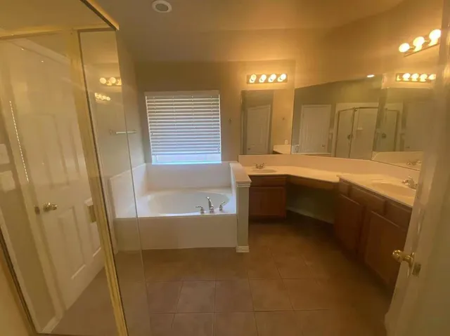 a bathroom with a tub sink shower and two mirror