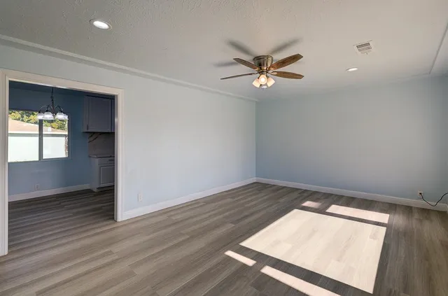an empty room with a ceiling fan and wooden floor