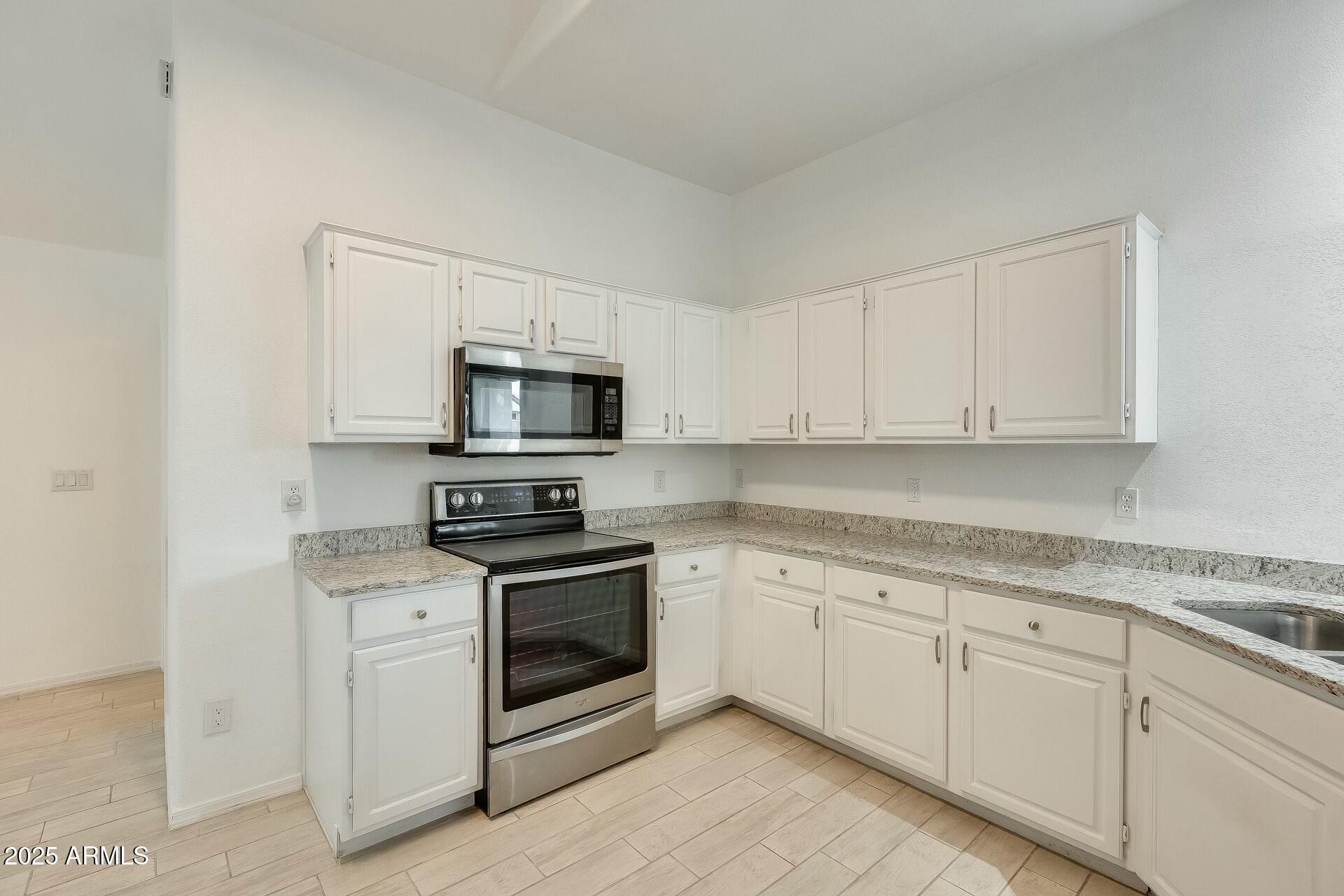 17514 North Rainbow Circle Surprise, AZ 85374 - Photo 17 of 69 a kitchen with granite countertop white cabinets and stainless steel appliances