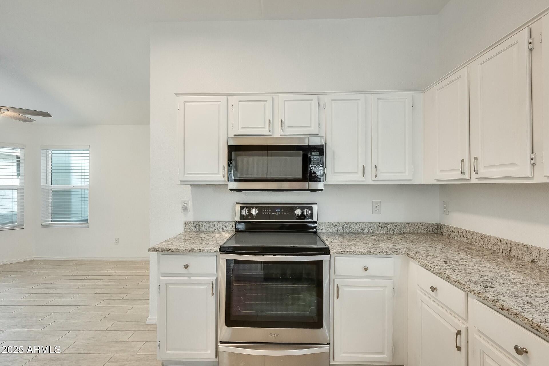 17514 North Rainbow Circle Surprise, AZ 85374 - Photo 18 of 69 a kitchen with granite countertop white cabinets and stainless steel appliances