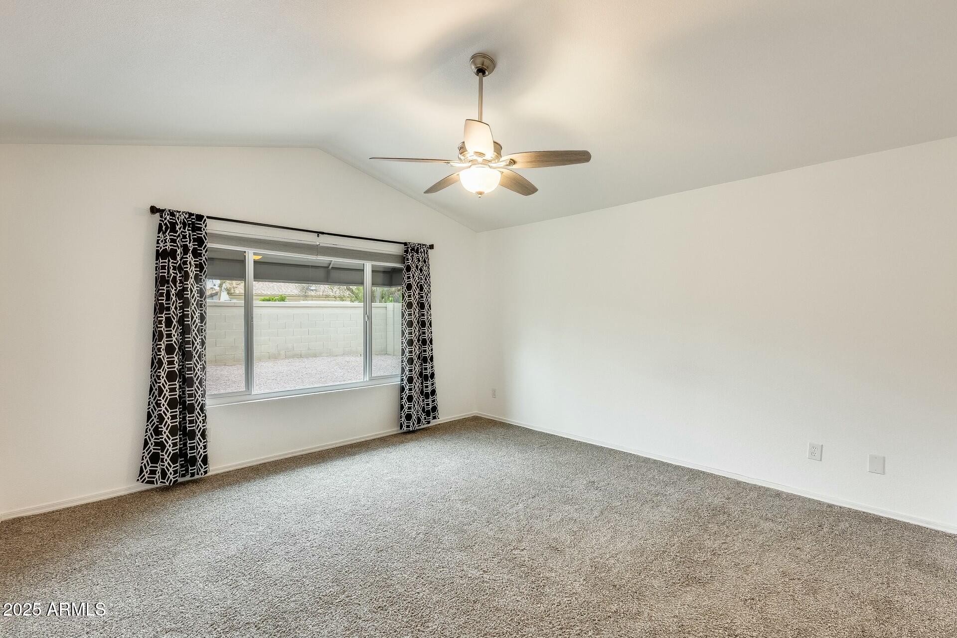 17514 North Rainbow Circle Surprise, AZ 85374 - Photo 27 of 69 an empty room with a chandelier fan and windows