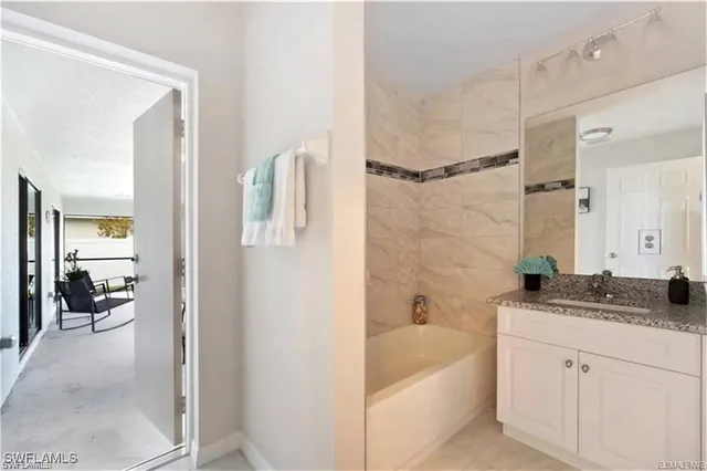 a bathroom with a granite countertop sink a mirror and a bathtub