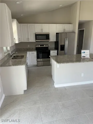 a large kitchen with stainless steel appliances a stove a sink a microwave and cabinets