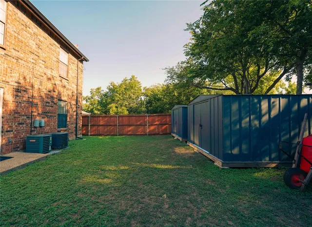 a view of a backyard with large trees and wooden fence