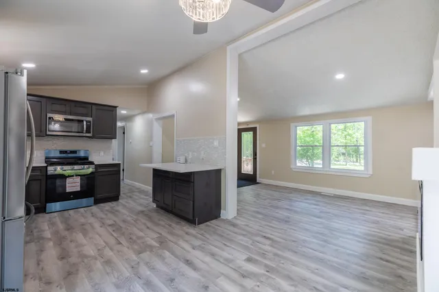a large kitchen with a large counter top space stainless steel appliances and a window