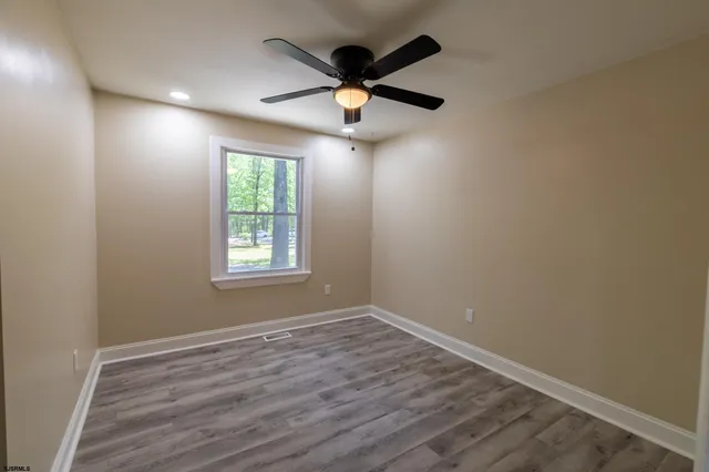 an empty room with ceiling fan and window