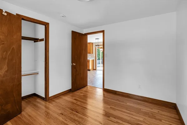 a view of an empty room with wooden floor and closet