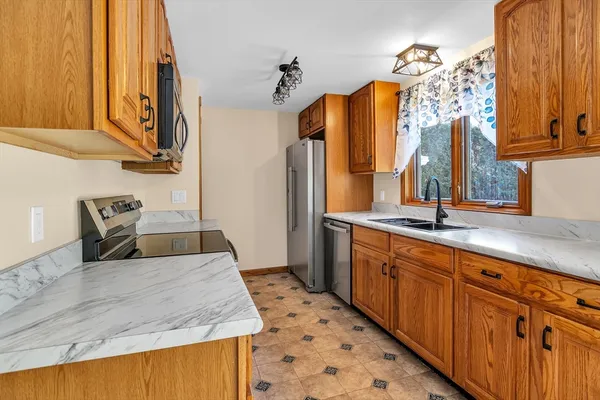 a large kitchen with stainless steel appliances granite countertop a sink and a refrigerator