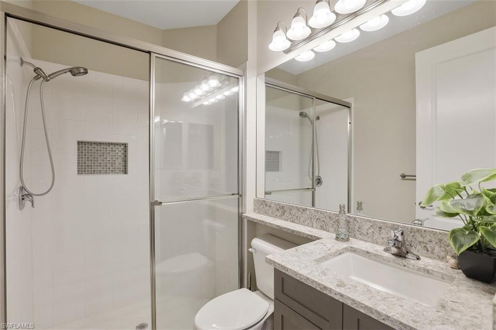 4334 Aurora Street Naples, FL 34119 - Photo 12 of 31 a bathroom with a granite countertop sink toilet and shower