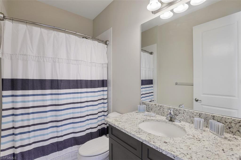 4334 Aurora Street Naples, FL 34119 - Photo 16 of 31 a bathroom with a sink a toilet and shower curtain