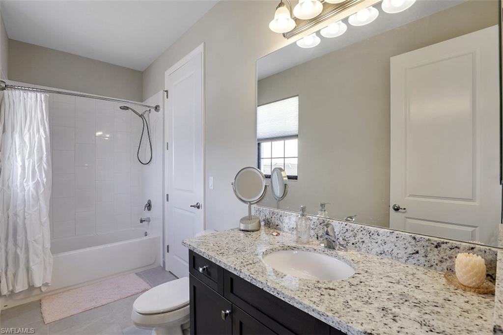 4334 Aurora Street Naples, FL 34119 - Photo 18 of 31 a bathroom with a granite countertop sink toilet mirror and shower