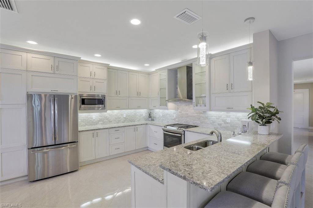 4334 Aurora Street Naples, FL 34119 - Photo 6 of 31 a kitchen with stainless steel appliances granite countertop a sink and a refrigerator