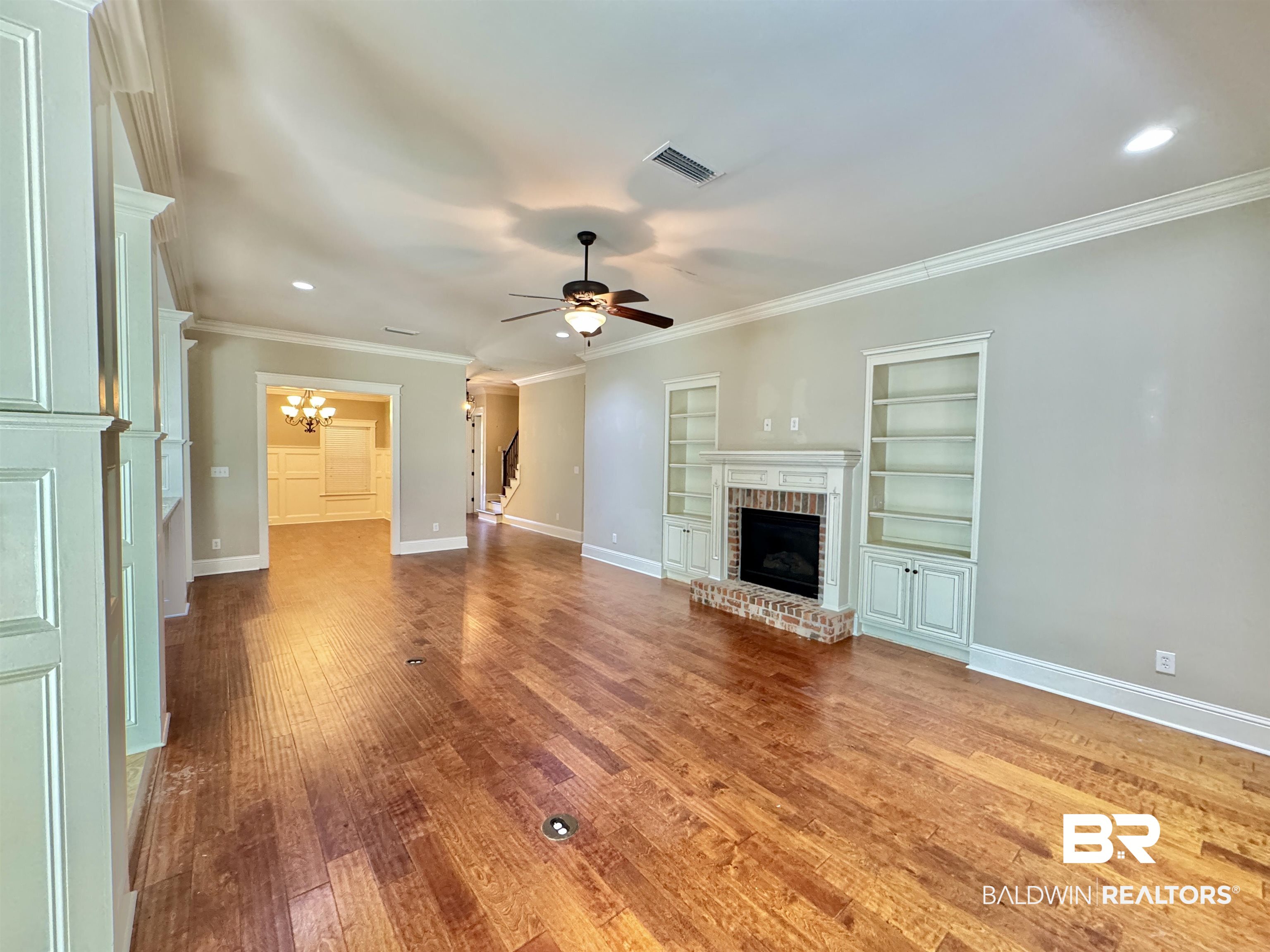 10846 County Road 138 Bay Minette, AL 36507 - Photo 38 of 53 Unfurnished living room featuring hardwood / wood-style floors, built in features, ceiling fan with notable chandelier, a fireplace, and crown molding