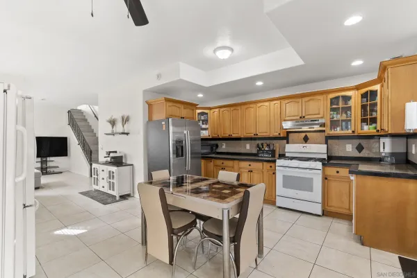 a kitchen with stainless steel appliances kitchen island granite countertop a table chairs and a refrigerator
