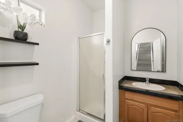 a bathroom with a granite countertop sink a toilet and a mirror
