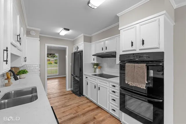 a kitchen with granite countertop a refrigerator a stove a sink and white cabinets