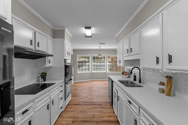 a kitchen with granite countertop a sink a counter space appliances and cabinets