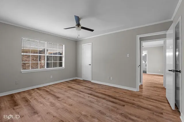 a view of empty room with wooden floor and fan