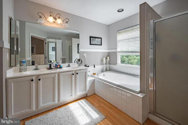 a spacious bathroom with a double vanity sink a mirror and a bathtub
