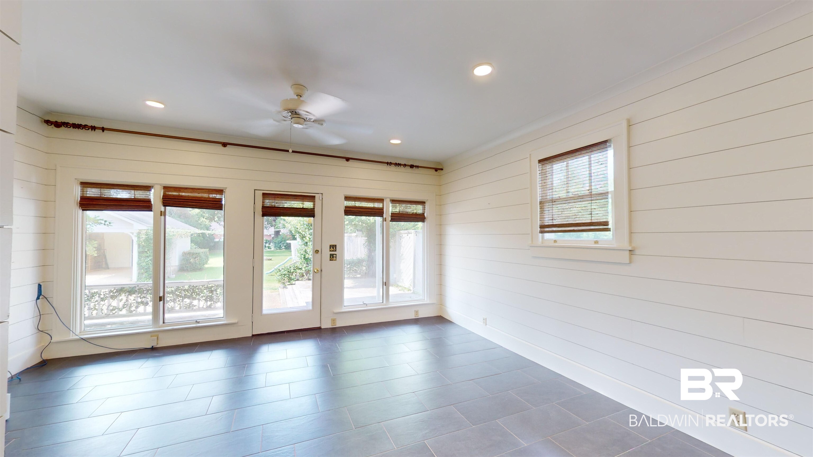 4307 Stein Street Mobile, AL 36608 - Photo 11 of 28 Empty room with wood walls, dark tile patterned floors, and ceiling fan