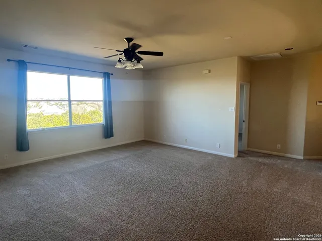 an empty room with windows and ceiling fan