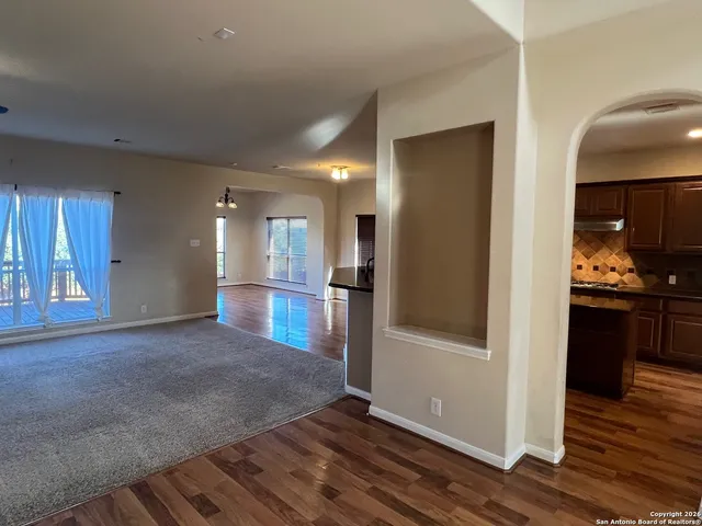 a view of a hallway with wooden floor and a kitchen