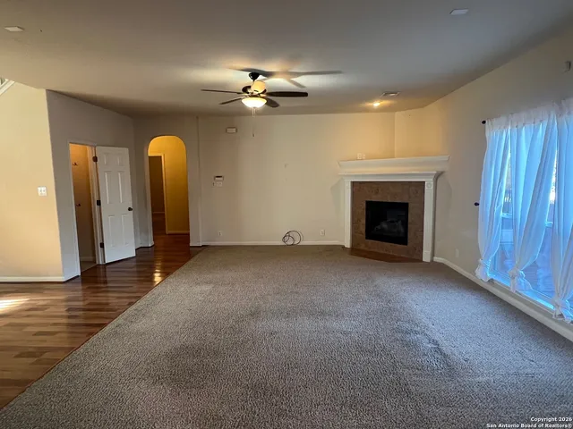 a view of an empty room with chandelier fan and fire place