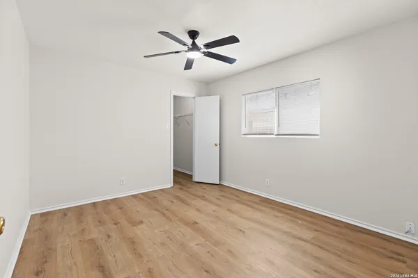 an empty room with wooden floor and ceiling fan