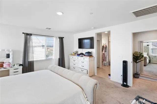 a bedroom with a bed and a flat tv screen on dresser