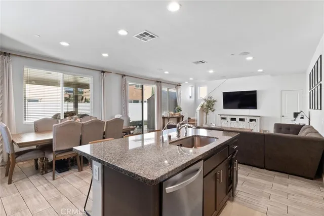 a living room with stainless steel appliances kitchen island granite countertop a table chairs and a flat screen tv