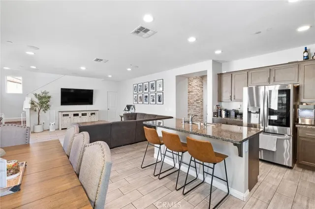 a living room with stainless steel appliances furniture a flat screen tv and a kitchen view
