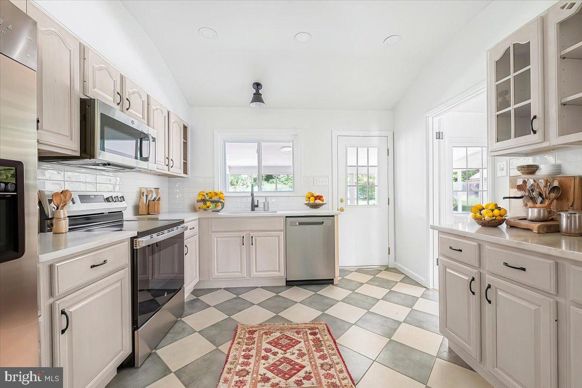 9619 Singleton Drive Bethesda, MD 20817 - Photo 4 of 25 a kitchen with stainless steel appliances a stove sink refrigerator and cabinets