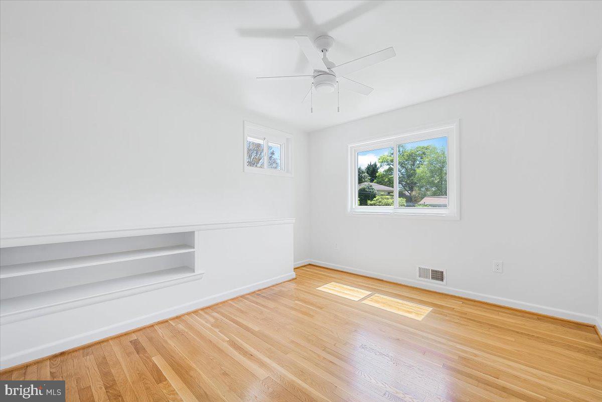9619 Singleton Drive Bethesda, MD 20817 - Photo 9 of 25 a view of empty room with wooden floor and fan
