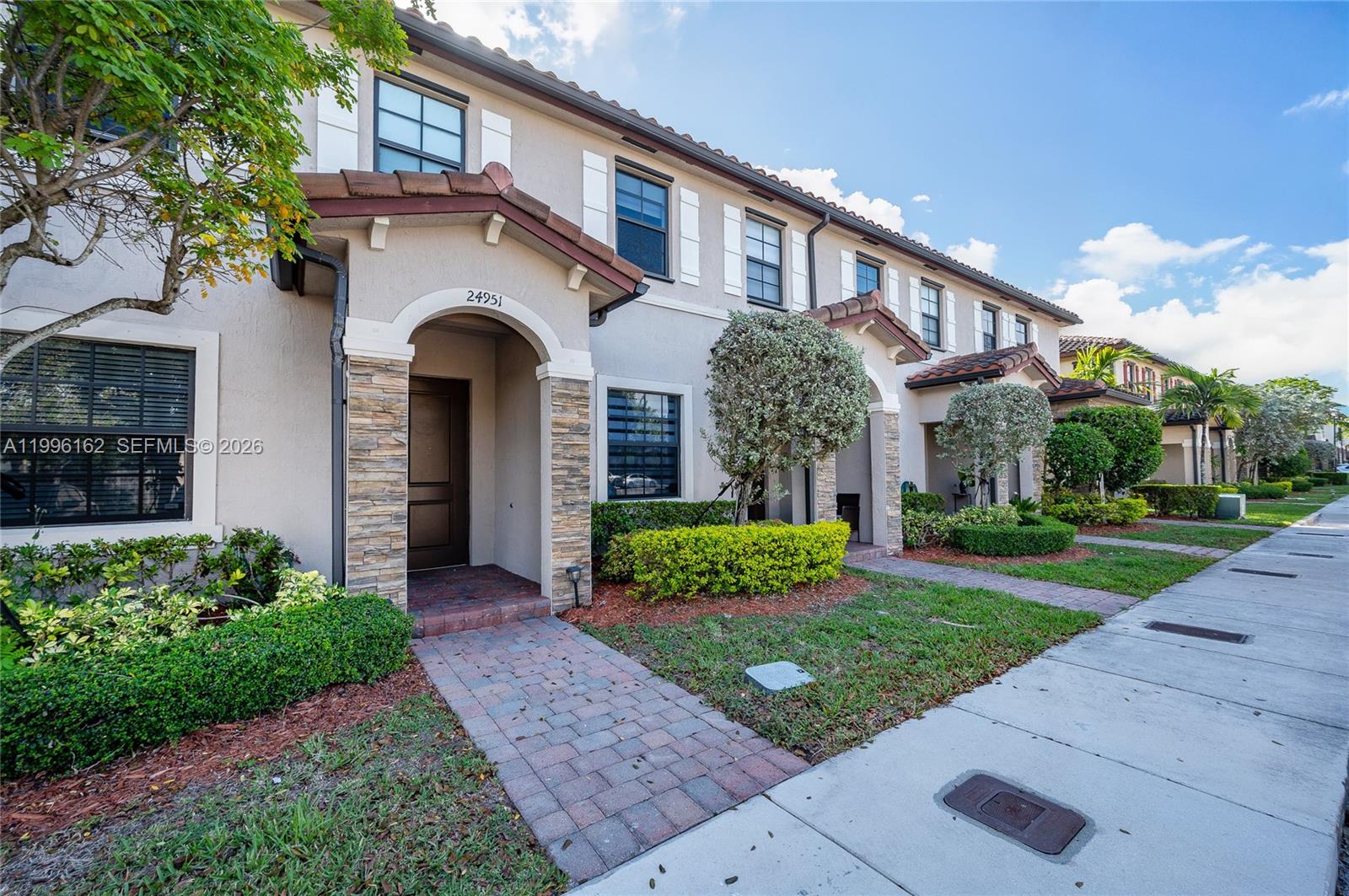 24951 Southwest 114th Court Homestead, FL 33032 - Photo 2 of 28 a front view of a house with a yard and potted plants