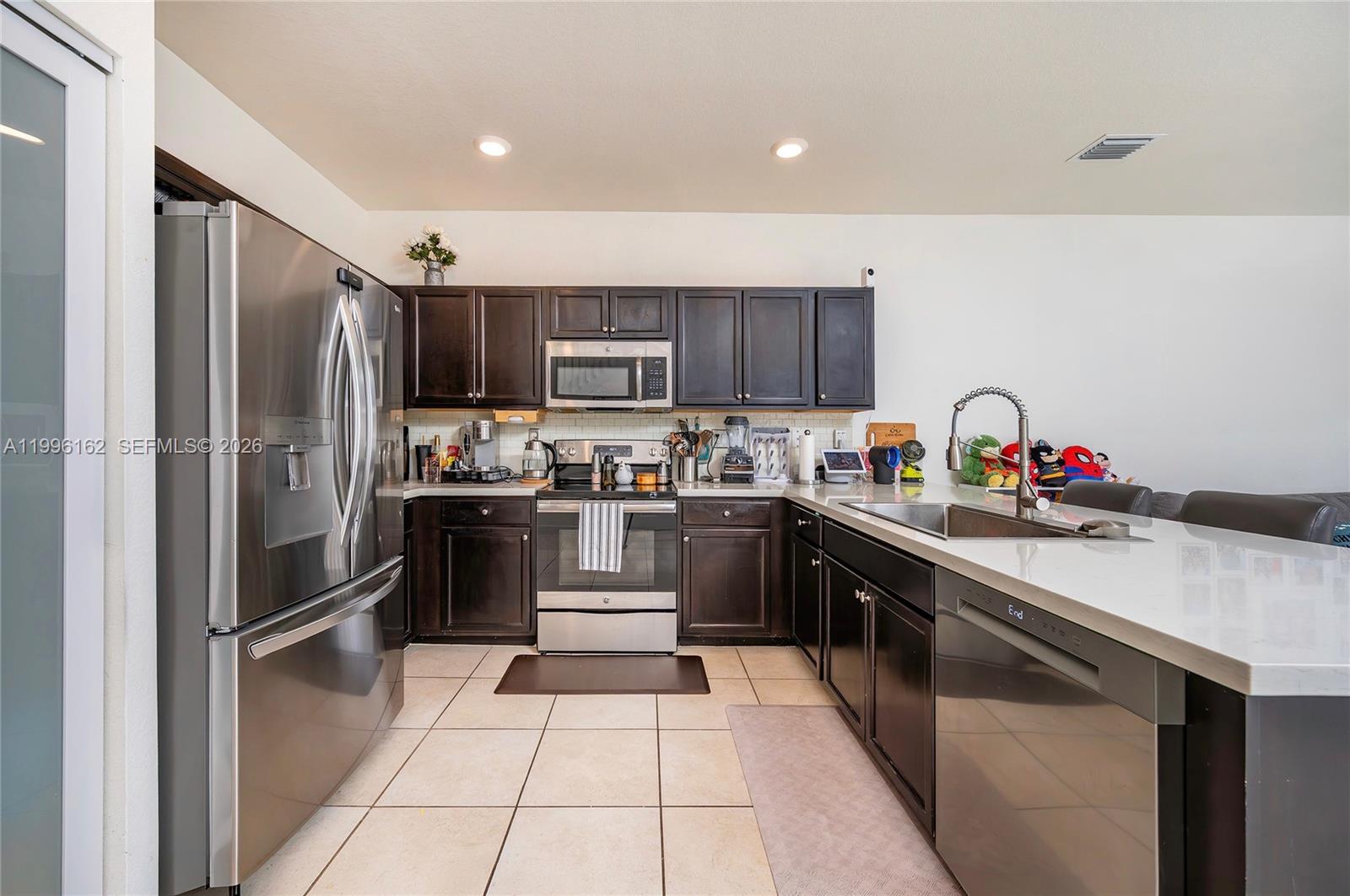 24951 Southwest 114th Court Homestead, FL 33032 - Photo 6 of 28 a kitchen with granite countertop stainless steel appliances and a refrigerator