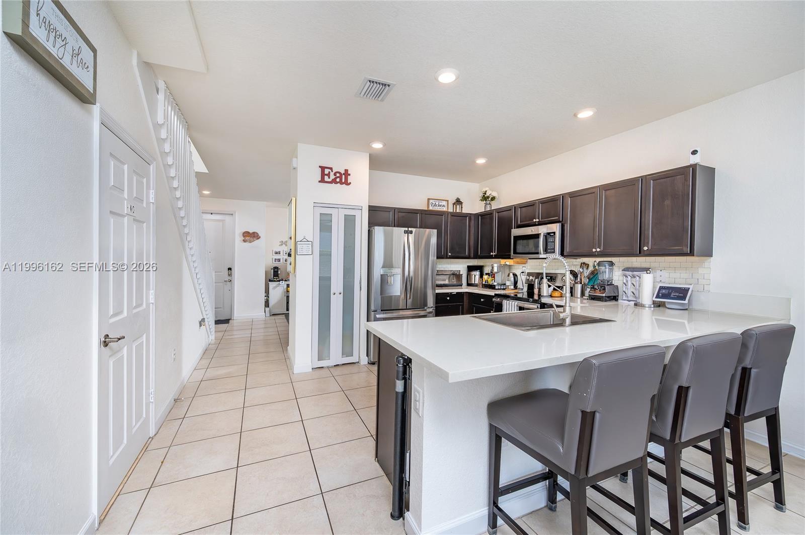 24951 Southwest 114th Court Homestead, FL 33032 - Photo 7 of 28 a kitchen with stainless steel appliances a refrigerator sink and wooden cabinets