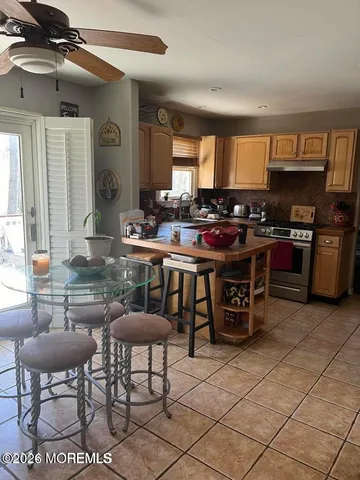 a kitchen with stainless steel appliances kitchen island granite countertop a stove a sink a dining table and chairs