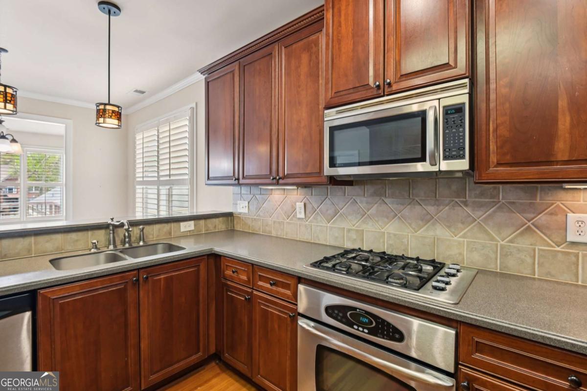 3180 The Commons Drive Cumming, GA 30041 - Photo 20 of 84 a kitchen with granite countertop a stove top oven cabinetry a sink and a window