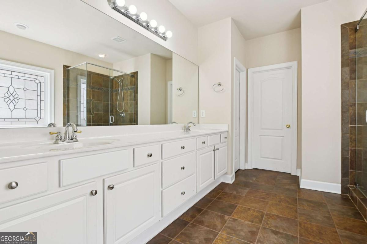 3180 The Commons Drive Cumming, GA 30041 - Photo 29 of 84 a bathroom with a double vanity sink a mirror and a