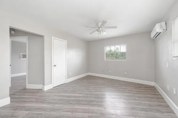 a view of an empty room with a window and wooden floor