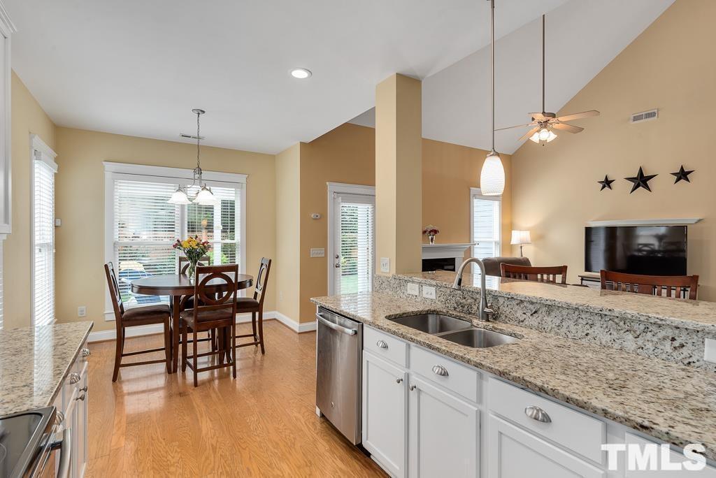 216 Frontgate Drive Cary, NC 27519 - Photo 13 of 26 a kitchen with granite countertop a sink a counter space dining table and stainless steel appliances