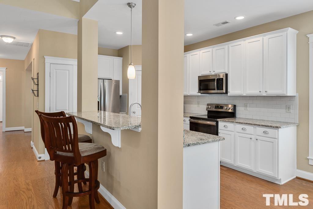 216 Frontgate Drive Cary, NC 27519 - Photo 14 of 26 a kitchen with stainless steel appliances kitchen island granite countertop a stove a sink a microwave and a refrigerator