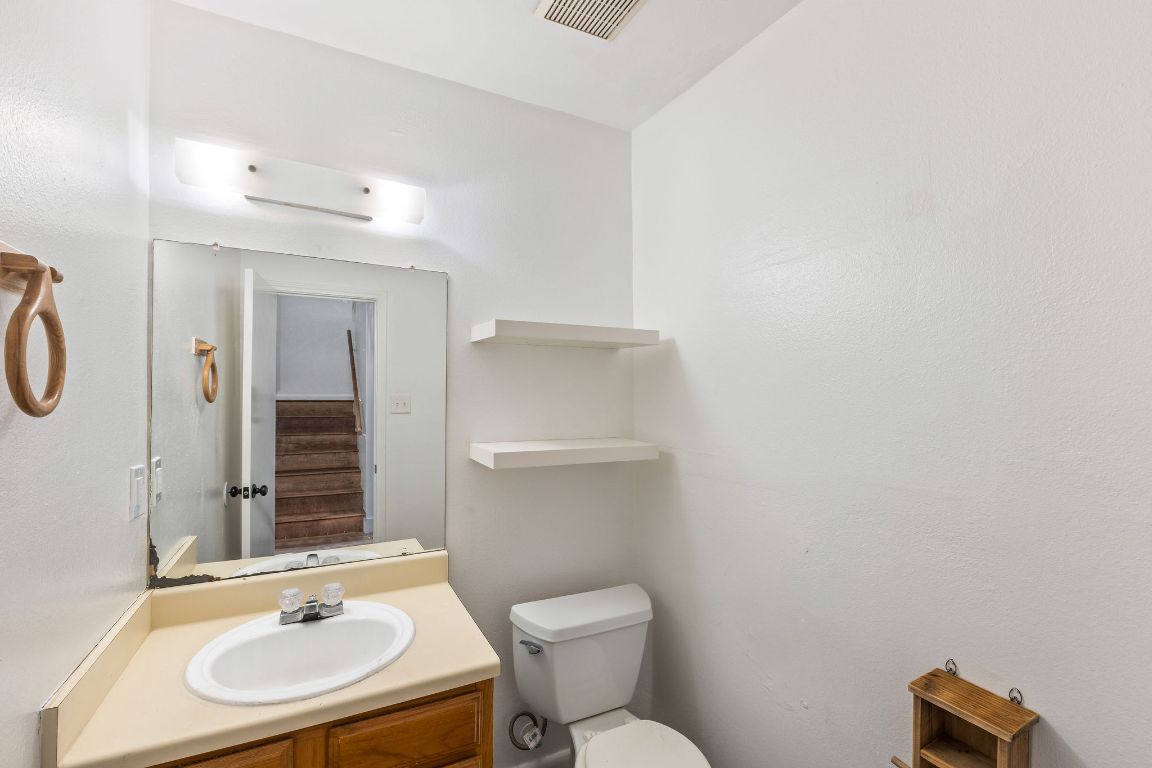 1712 Timber Ridge Road Austin, TX 78741 - Photo 15 of 35 a bathroom with a sink toilet a mirror and vanity