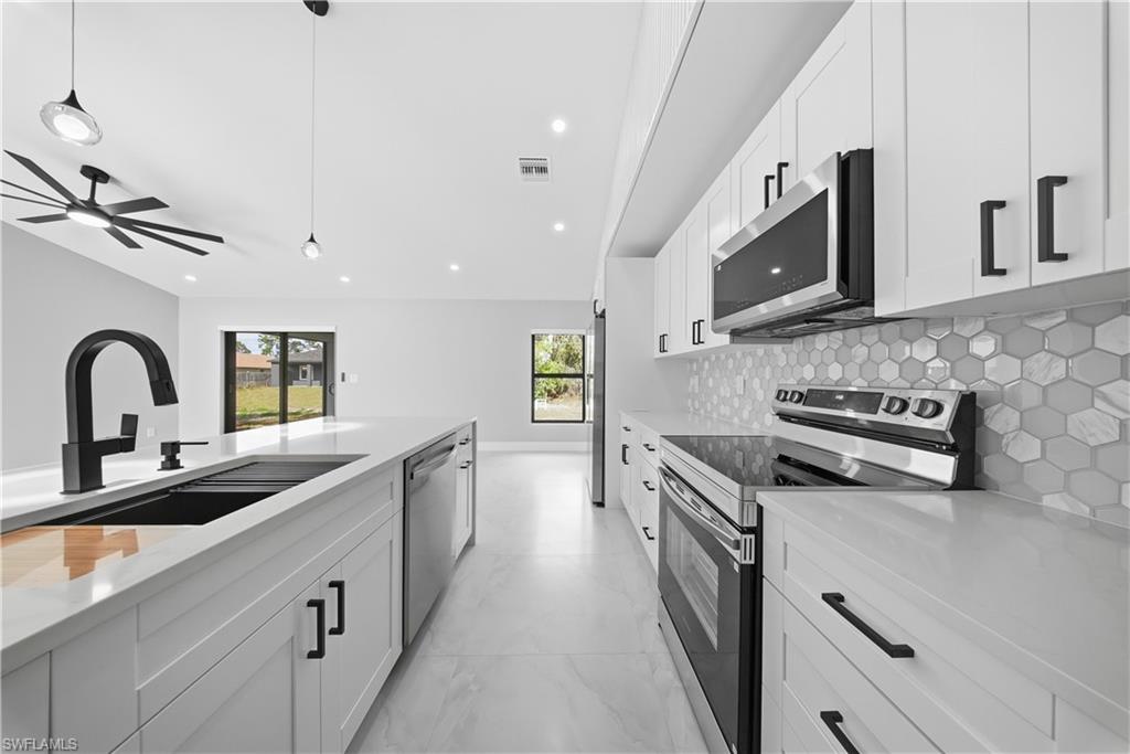 3406 25th Street Southwest Lehigh Acres, FL 33976 - Photo 11 of 44 a kitchen with stainless steel appliances granite countertop a sink and stove