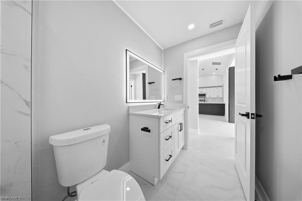 3406 25th Street Southwest Lehigh Acres, FL 33976 - Photo 19 of 44 a bathroom with a toilet sink and mirror