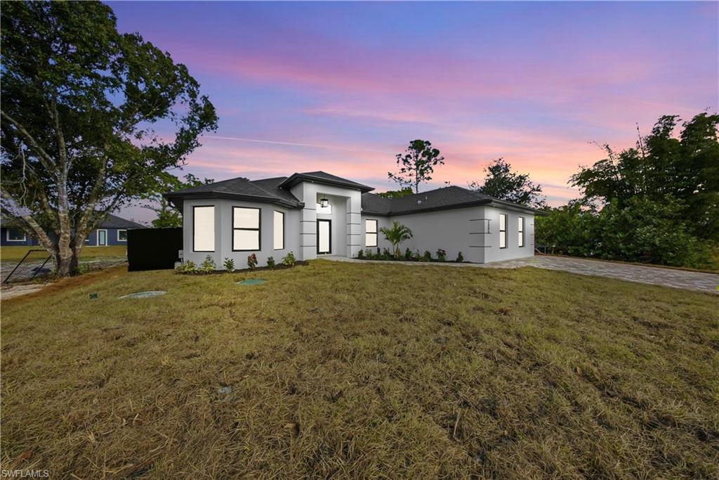 3406 25th Street Southwest Lehigh Acres, FL 33976 - Photo 2 of 44 a front view of a house with a garden and yard