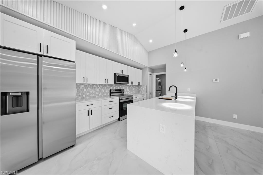 3406 25th Street Southwest Lehigh Acres, FL 33976 - Photo 9 of 44 a kitchen with white cabinets and stainless steel appliances