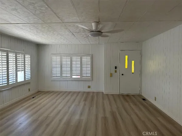 a view of an empty room with a window and wooden floor