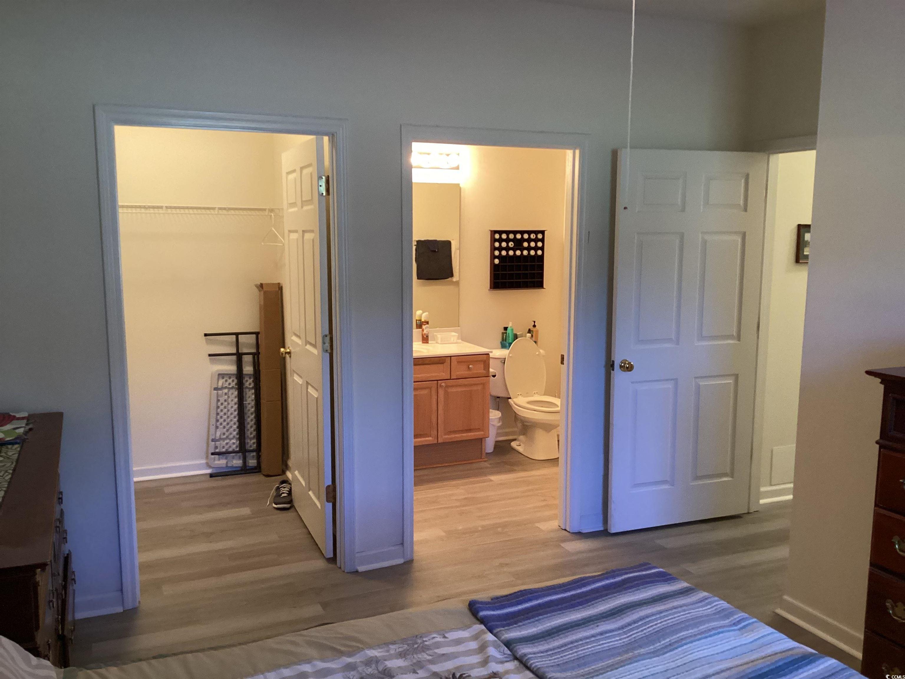 4430 Lady Banks Lane, Unit C1 Murrells Inlet, SC 29576 - Photo 21 of 34 Bedroom with dark wood finished floors, a spacious closet, and ensuite bath