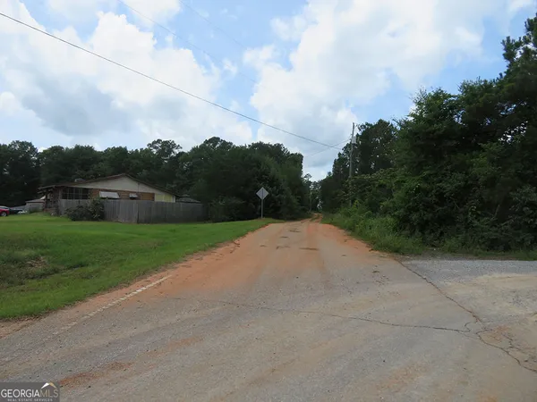 a view of city street with a big yard of the house and trees all around